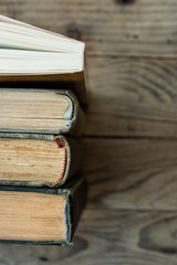 Old and new books arranged in a row, top view of spines, aged wood background, school, education, learning, reading concept, copyspace