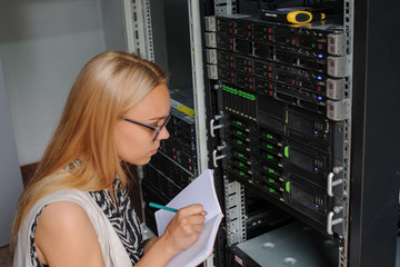 Young woman engineer It between the server racks in the data center