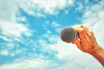 Female hand with microphone on background