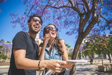 Tourist couple holding map laughing