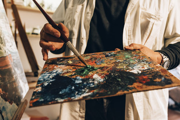 Close up of man artist painting oils in his studio.