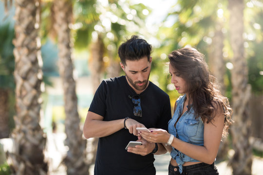 Couple standing outside holding smartphones