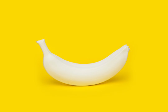 Banana painted white on yellow background