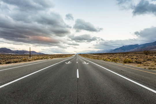 Straight road with direction arrows in Death Valley National Park, California, USA