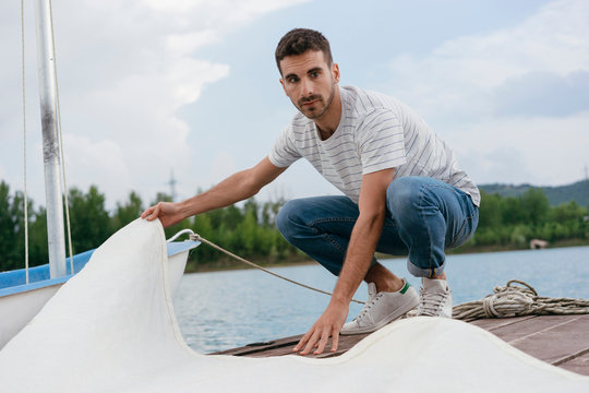 Young man folding boat's sail