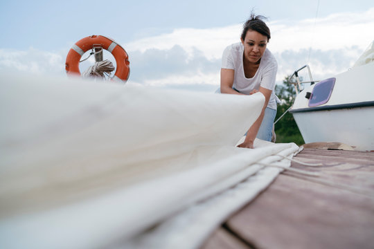 Young woman folding boat's sail