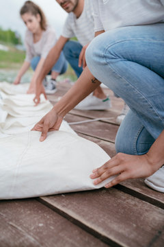 Three friends, folding boat's sail, low section