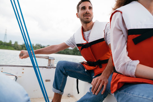 Man and woman on sailing boat, man steering boat