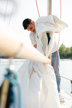 Man on sailing boat, taking down sail