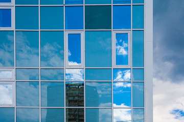 Modern facade of glass and steel reflecting sky and clouds
