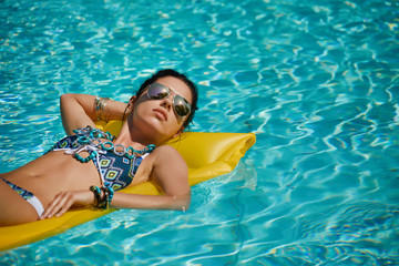 Young happy woman relaxing in a swimming pool