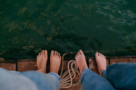 Two women, standing on pier, barefoot, overhead view