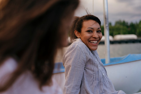 Two women, relaxing on pier, smiling