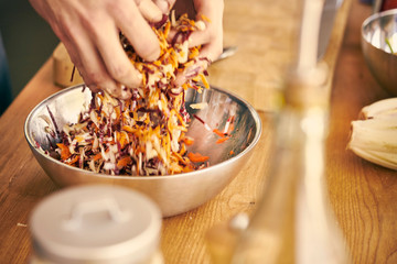 Cropped view of chef tossing salad with hands
