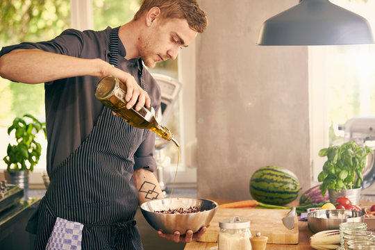Chef drizzling oil on bowl of food