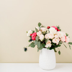 Beautiful flowers bouquet in flowerpot in front of pale pastel beige wall. Floral lifestyle composition.