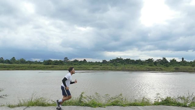 Man jogging on the river side while rain coming, slow motion shot at 120fps.