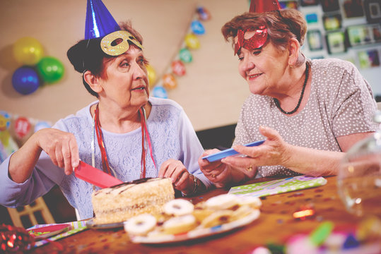 Senior women serving birthday cake at party
