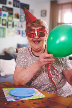 Senior woman waving balloons at birthday party