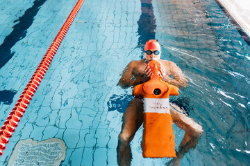 Senior man preparing lifesaving training equipment in swimming pool
