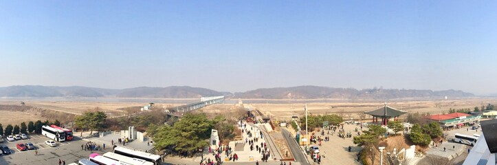 Panoramic view of tourists visiting the no-man's-land between the border of North & South Korea (Asia) in Imjingak: brown sand desert, hills / mountains separate the demilitarized war zone (DMZ)