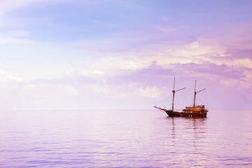 Wooden sailboat in the Indian ocean under cloudy sky on sunrise, Indonesia. Nature vast sea background.