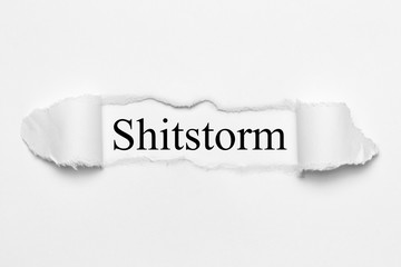 Shitstorm on white torn paper