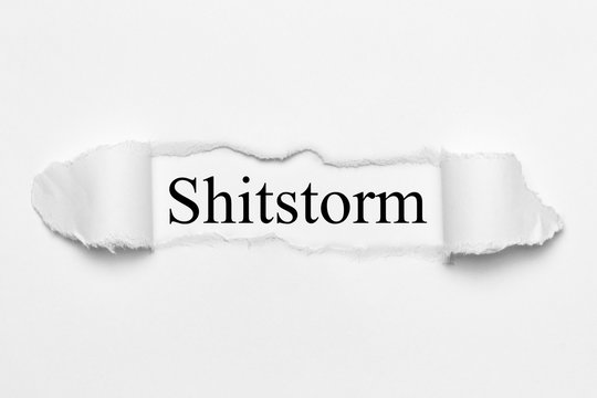 Shitstorm on white torn paper