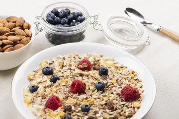 Cereal bowl breakfast with milk, raspberries and blueberries next to bowl with almonds. Horizontal studio shot.