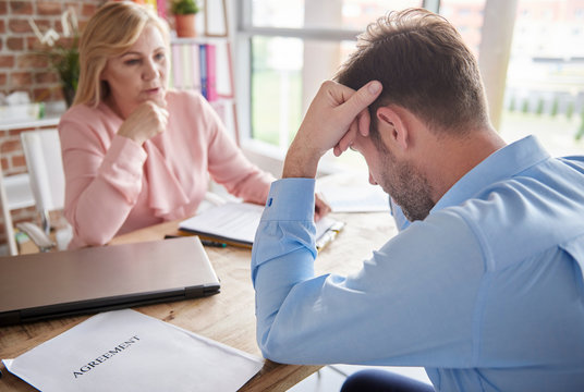 Manager in office reprimanding employee with head in hands