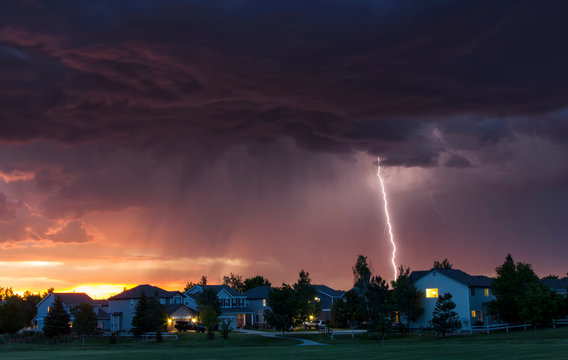 Forked lightning in orange sky over urban area, Aurora, Colorado, United States, North America