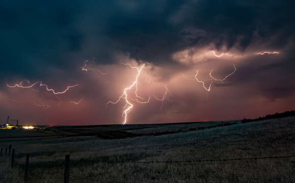 Forked lightning in orange sky over rural area, Grant, Nebraska, United States, North America
