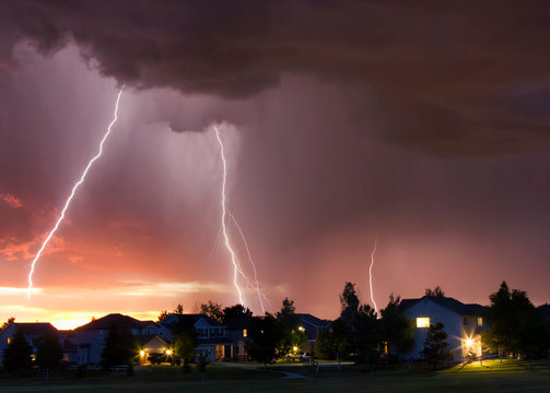 Forked lightning in orange sky over urban area, Aurora, Colorado, United States, North America