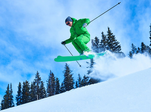 Man jumping while skiing down snow covered mountainside, Aspen, Colorado, USA