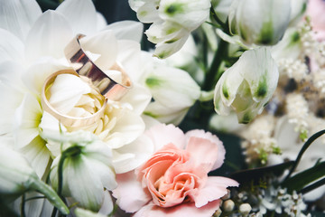 Wedding rings on decorative flowers background.