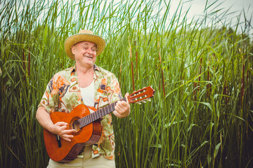 Mature funny european man on vacation resting and  playing guitar singing songs, having fun from...