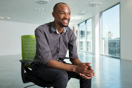 Portrait of businessman, sitting in chair, in empty office space