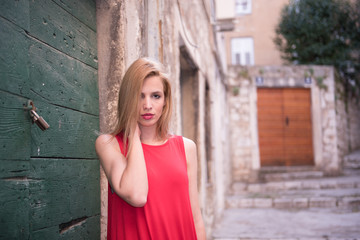 Fototapeta premium Outdoor close up portrait of model woman in fashionable red dress.City lifestyle.City lifestyle.Female fashion concept.Retro and vintage filter and colors effect used.