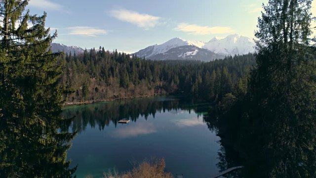 Aerial footage of a beautiful lake in the forest with mountains in the background. Shot in Flims, Switzerland in 4k quality.