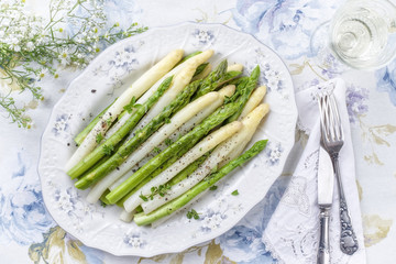 Boiled green and white Asparagus as top view on a plate