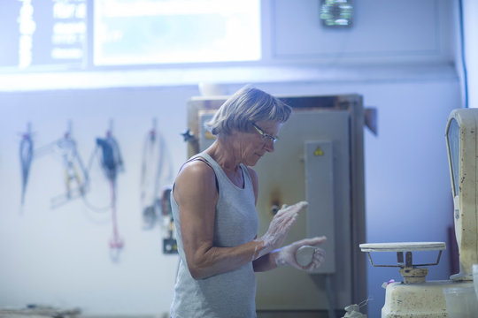 Senior woman in pottery workshop, weighing clay for pottery project
