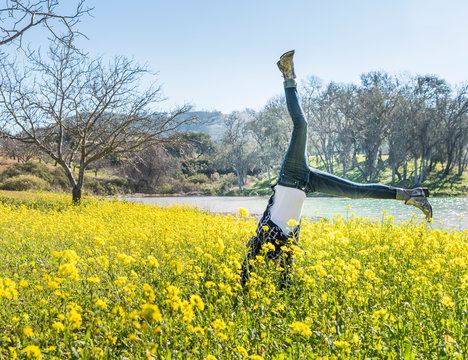 Mature woman doing cartwheel in field of wild flowers, Paso Robles, California, USA