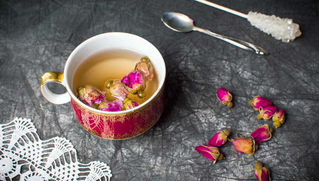 Rose tea in a cup on dark fabric