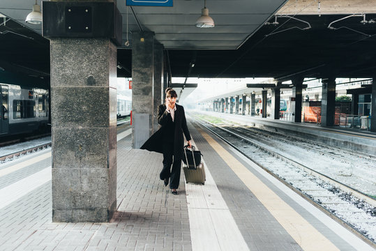 Businesswoman using mobile phone in train station, Milan, Italy
