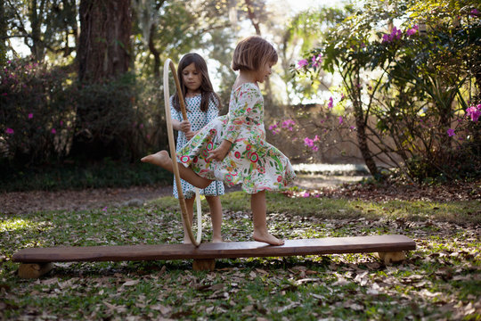 Girl holding plastic hoop, sister running through