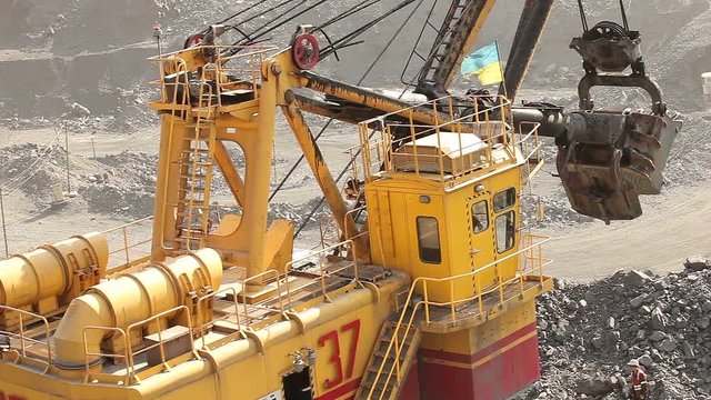 Industrial excavator and working man in a quarry, a large jaded industrial excavator. A large mining excavator is loading a mining truck in an iron ore quarry.