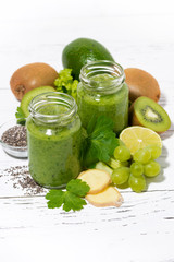 healthy green fruit and vegetable smoothies in jars on white background, vertical