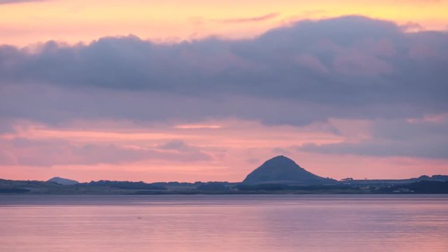 Time lapse footage of the Firth of Forth bay at sunrise with the Berwick Law Hill at the distance. Portobello Beach, Edinburgh, Scotland, UK 