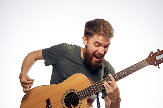 Young guy with a beard on a white isolated background playing a guitar