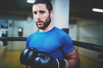 Young caucasian athlete in black gloves looking at the camera.Blurred background.Horizontal.